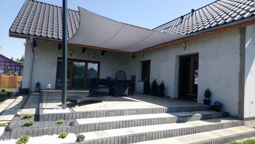 Weißes Sonnensegel wasserdicht nach Maß montiert über der Terrasse eines modernen Einfamilienhauses