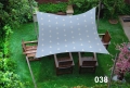 Toldo vela gris 3x4 m con estampado de anclas sobre muebles de madera en el césped
