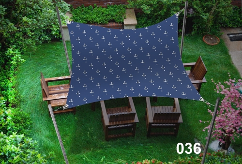 Blue 3x4.5m waterproof sun shade sail with white anchor pattern over a garden patio set turn with four wooden chairs