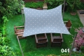 Toldo vela impermeable 3x4,5 m con estampado de puntos colgado sobre muebles de jardín de madera en el césped