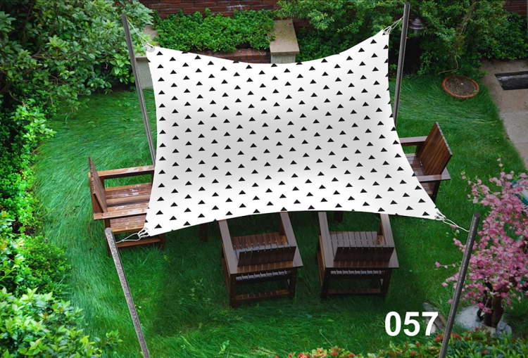 Triangle pattern garden sail shade 3x4.5 m over a wooden patio set with chairs on green grass