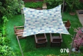 Toldo vela impermeable 3x4,5 m con motivos azules sobre muebles de madera en el césped