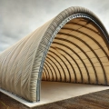 Custom-made tarpaulin cover for a large arched hangar building with a metal frame and concrete floor