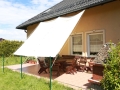 Vela ombreggiante scorrevole impermeabile che copre un terrazzo con mobili da giardino