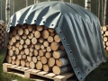 Durable grey tarp covering a neatly stacked wood pile on a pallet in a forest setting
