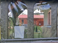 Custom-made transparent terrace tarp with a stone wall print and arched window cutouts for an outdoor patio enclosure.