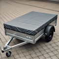 Custom-sized grey protective cover for a small utility car trailer on a paved surface