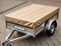 Remorque de voiture grise avec bâche de protection beige assortie, stationnée sur des pavés