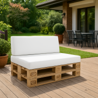 White outdoor cushions on a wooden pallet sofa set on a modern patio with a green garden background.