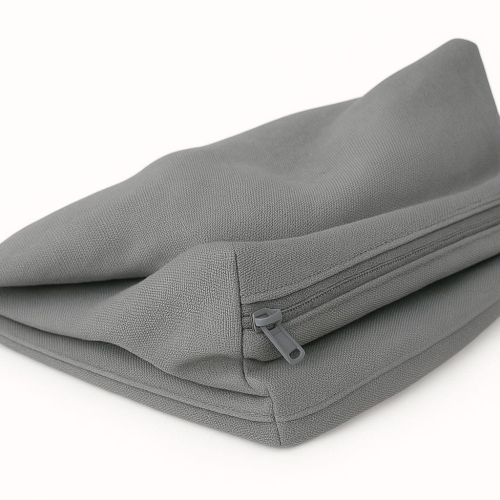 Folded grey outdoor cushion cover with a zipper closure and durable woven fabric texture turns away against a white background
