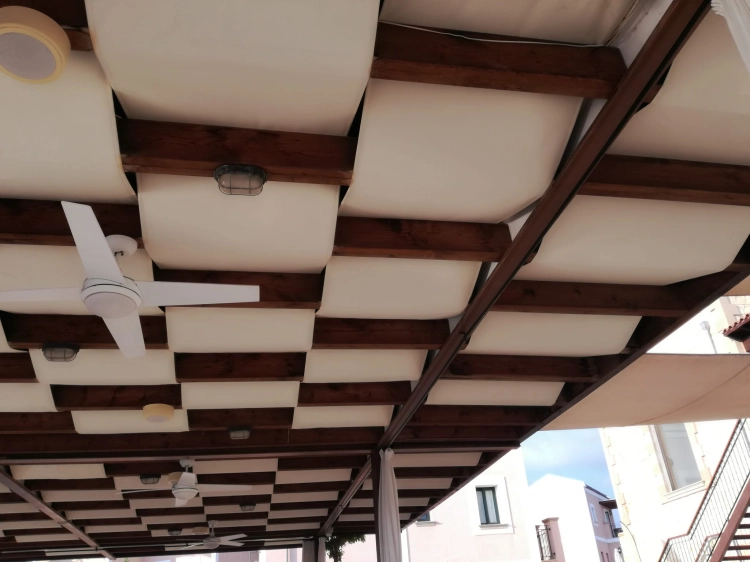 Custom waterproof garden pergola sunshade fabric strips installed between dark wooden beams with ceiling fans.