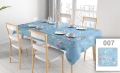 Custom blue floral tablecloth on a dining table with chairs and place settings in a bright room