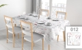 Floral pattern tablecloth on a dining table with four chairs and set dishware in a bright room.