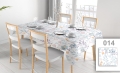 Floral pattern stain-resistant tablecloth on a dining table with chairs and place settings in a bright room