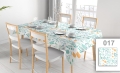 Custom stainproof floral tablecloth with orange and teal flowers on a dining table with chairs and place settings.