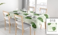 Customizable stain-resistant tablecloth with watercolor monstera leaf print on a set dining table with chairs