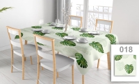 Customizable stain-resistant tablecloth with watercolor monstera leaf print on a set dining table with chairs