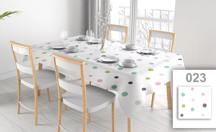 Weiße fleckabweisende Tischdecke mit bunten Punkten auf einem Esstisch mit vier Stühlen und elegantem Geschirr