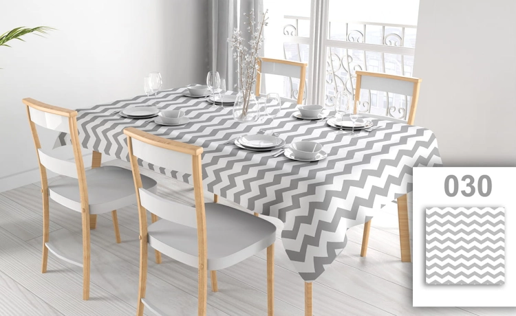 Custom stain-resistant tablecloth with grey and white chevron pattern on a dining table with chairs and place settings