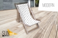 Wooden deck chair with a custom geometric pattern seat on a modern patio.
