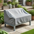 Gray waterproof custom-fit protective cover for two-seater garden sofa on a stone patio with potted plants
