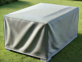 Light grey waterproof custom outdoor furniture cover protecting a rectangular garden table on a green lawn