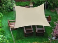 Sonnenschutz wasserdichtes Sonnensegel beige über Holzstühlen im Garten an vier Masten