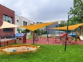 Toldos vela amarillos a medida instalados sobre un moderno parque infantil con arena y casitas para niños