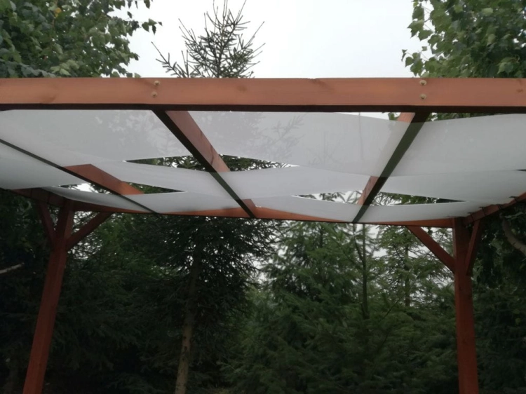 Weißes Sonnensegel für die Gartenlaube, verflochten durch das Dach einer Pergola aus Holz