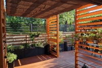 Tenda a pacchetto marrone parasole in HDPE montata su una pergola in legno sopra un elegante terrazzo con piante