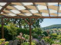Toldo para pérgola de doble urdimbre en beige y blanco, material impermeable que protege la terraza del sol