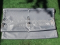 Tira gris impermeable para pérgola con mosquetones, colocada sobre hierba verde antes del montaje