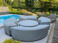 Custom grey protective covers on garden furniture set near an outdoor swimming pool and lush landscaping