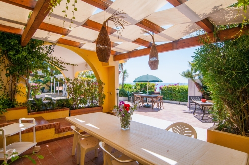 Günstiges Sonnenschutzsegel nach Maß unter einer Holzpergola mit Blick auf Terrasse und Meer