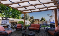 White waterproof sunshade panels woven through a wooden pergola over a patio with outdoor furniture and a fireplace