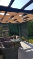 Toldo impermeable para pérgola de 0,7x5 m entrelazado en el techo de una moderna estructura de jardín oscura