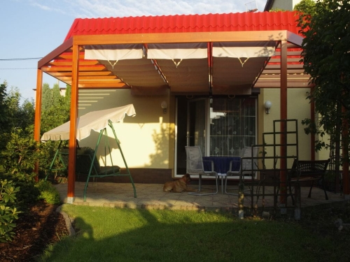 Horizontal 3x4m Roman blind with light beige waterproof fabric installed on a wooden terrace pergola under a red roof