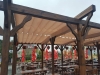 Beige waterproof Roman wave shade sail for 3x4 m terrace pergola over wooden outdoor restaurant tables