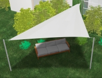 White triangular sun shade sail over an outdoor sofa on a lawn with green bushes.