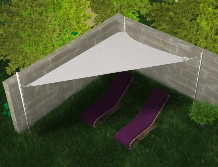 Triangular white sun shade sail mounted over two purple lounge chairs on a lawn by a garden wall