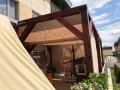 Tenda premium su misura montata su una pergola da terrazzo in legno con copertura chiara