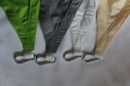 Vier Ecken von Premium-Sonnensegeln in den Farben Grün, Grau, Weiß und Beige mit Metallkarabinern