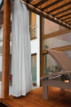 Custom white outdoor curtain for terraces on a modern wooden deck with a lounge chair and pergola