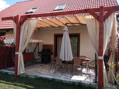 Custom waterproof sun shade Roman blind installed on a wooden pergola over a patio seating area with a table and chairs