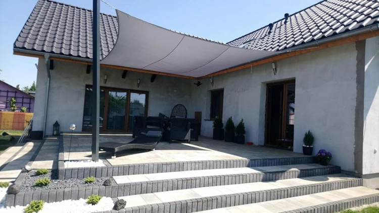 Large waterproof 3x4m charcoal gray rectangle shade sail over a stone patio with outdoor furniture and stairs.