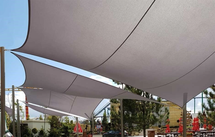Vodotesná štvorcová slnečná clona 4x4 m v šedej farbe nad terasou a záhradnou kaviarňou