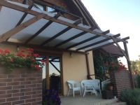 Rechthoekig wit schaduwdoek 3,2x2,5 m gemonteerd op een houten pergola boven het terras met tuinmeubelen
