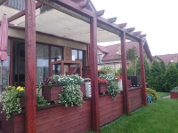 Weißes rechtwinkliges Sonnensegel 3,2x4,2 m montiert auf einer Holzpergola über einer Terrasse mit Blumen
