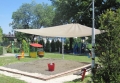 Toldo vela de jardín beige 3,2x5 m instalado sobre un arenero en un parque infantil