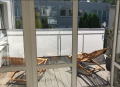 Custom-made white balcony privacy screen attached to a metal railing overlooking a wooden deck with lounge chairs